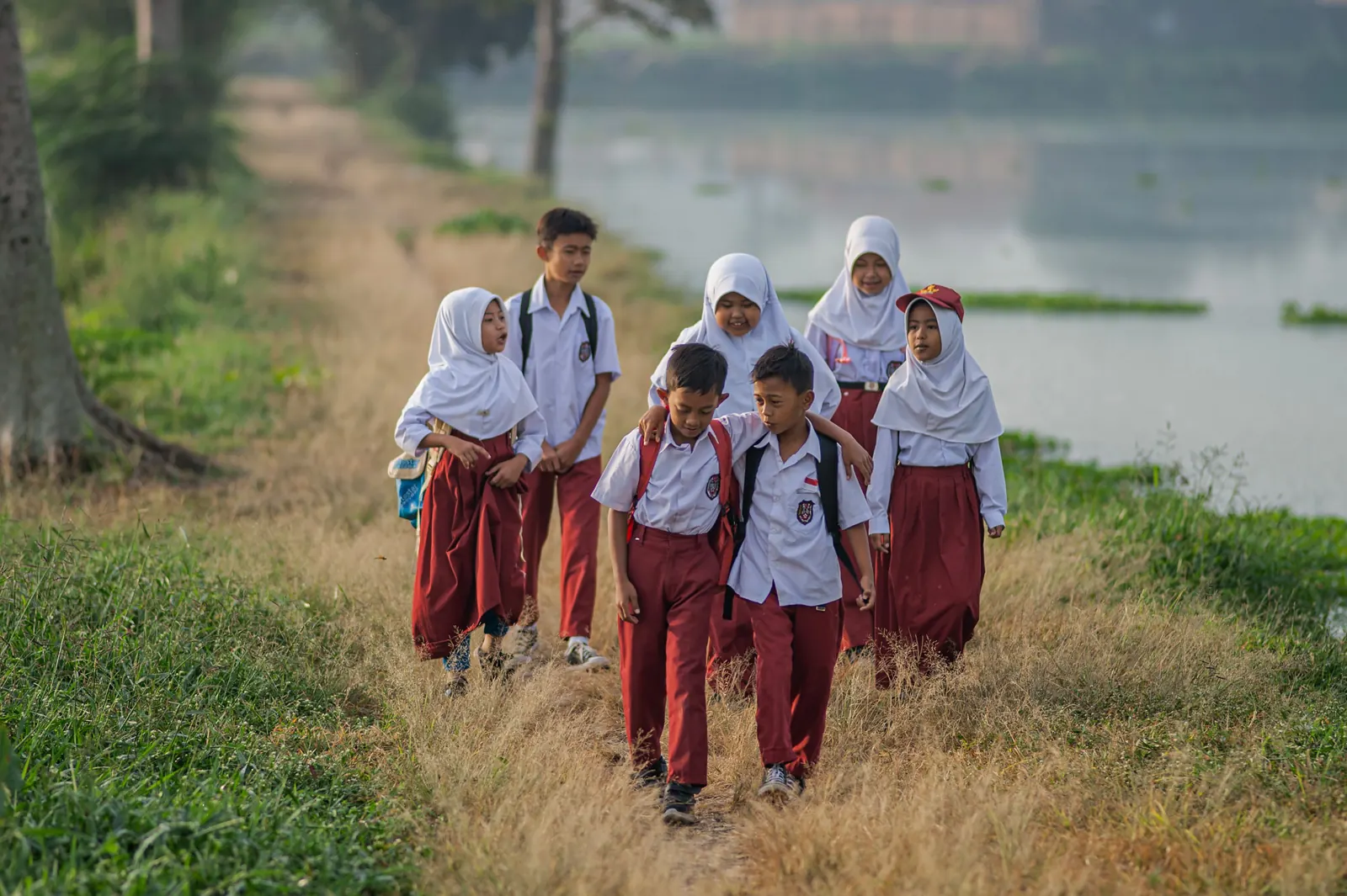 Siswa berjalan menuju sekolah di tepi jalan